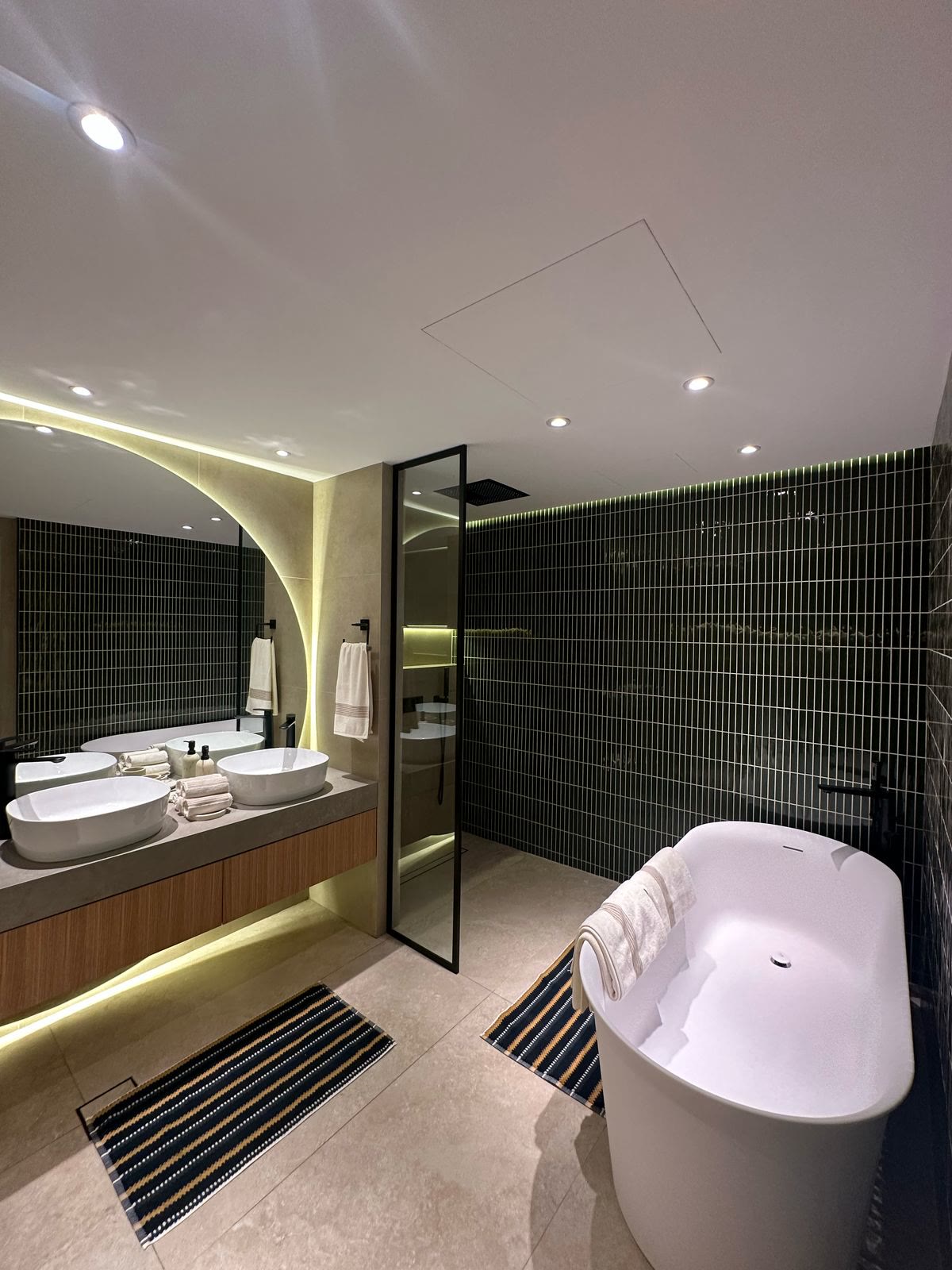 Completed master bathroom with stone vanity and illuminated mirror