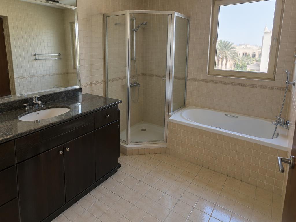 Small beige-tiled master bathroom before renovation in Al Hamra Village
